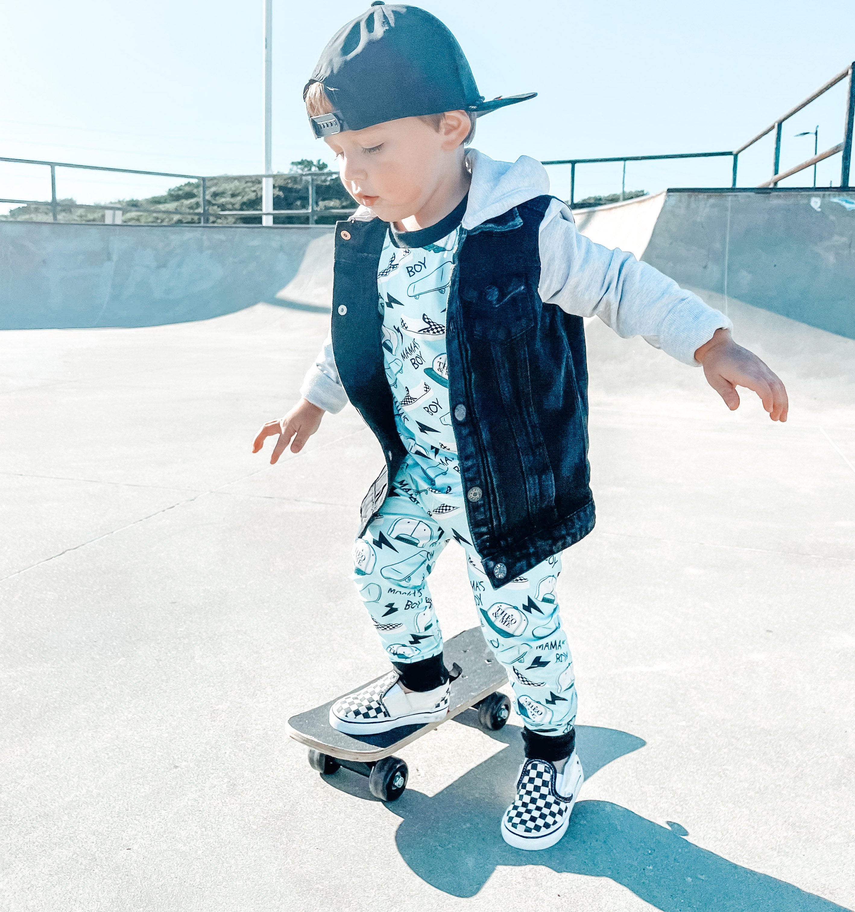 Boy wearing the Boys 2-Piece Short Sleeve Pajamas - Blue Mamas Boy Skateboards plus lightning bolts, sneakers, and theo & me hats as the pattern