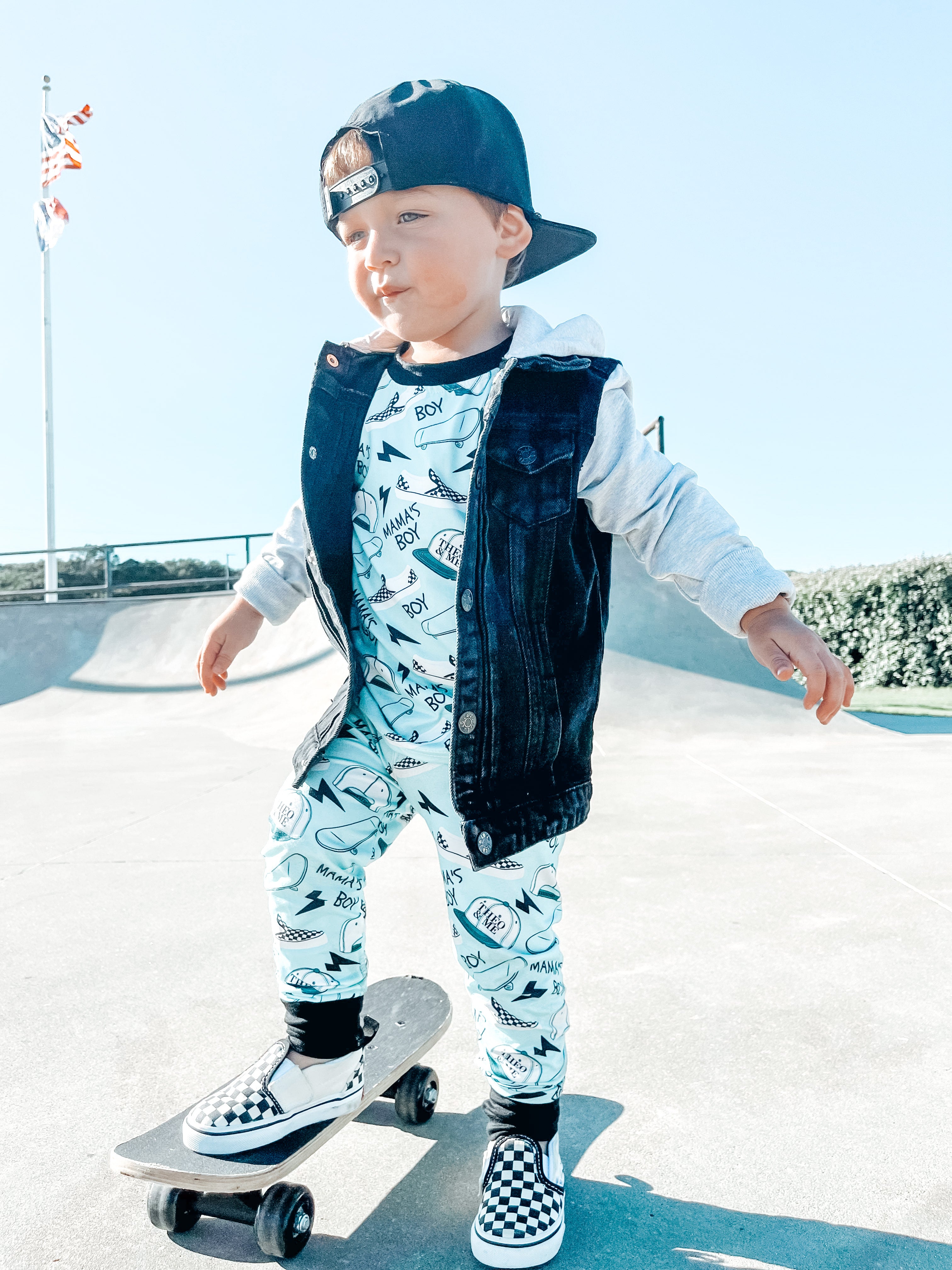 Boy wearing the Boys 2-Piece Short Sleeve Pajamas - Blue Mamas Boy Skateboards plus lightning bolts, sneakers, and theo & me hats as the pattern