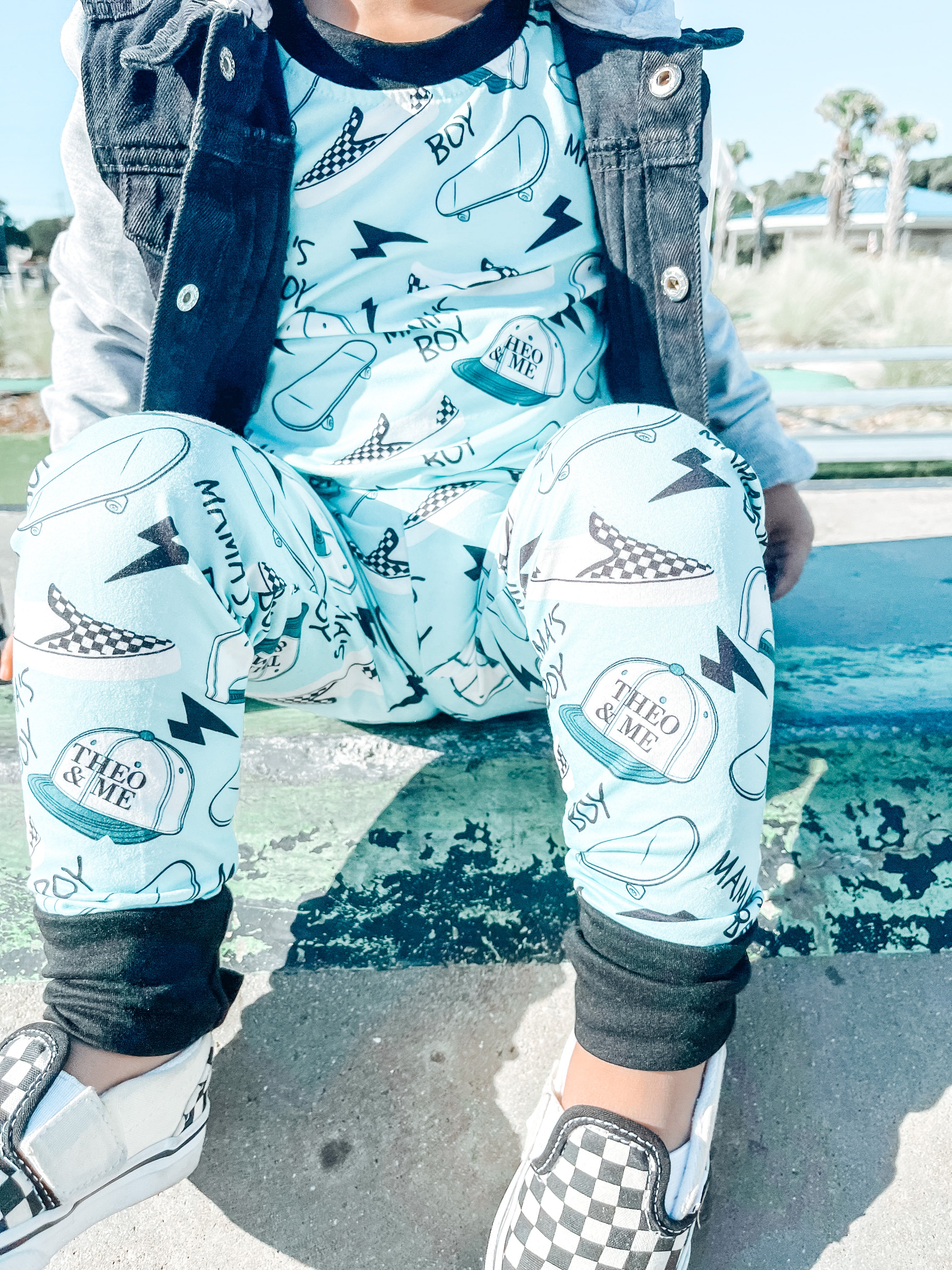 Boy wearing the Boys 2-Piece Short Sleeve Pajamas - Blue Mamas Boy Skateboards plus lightning bolts, sneakers, and theo & me hats as the pattern