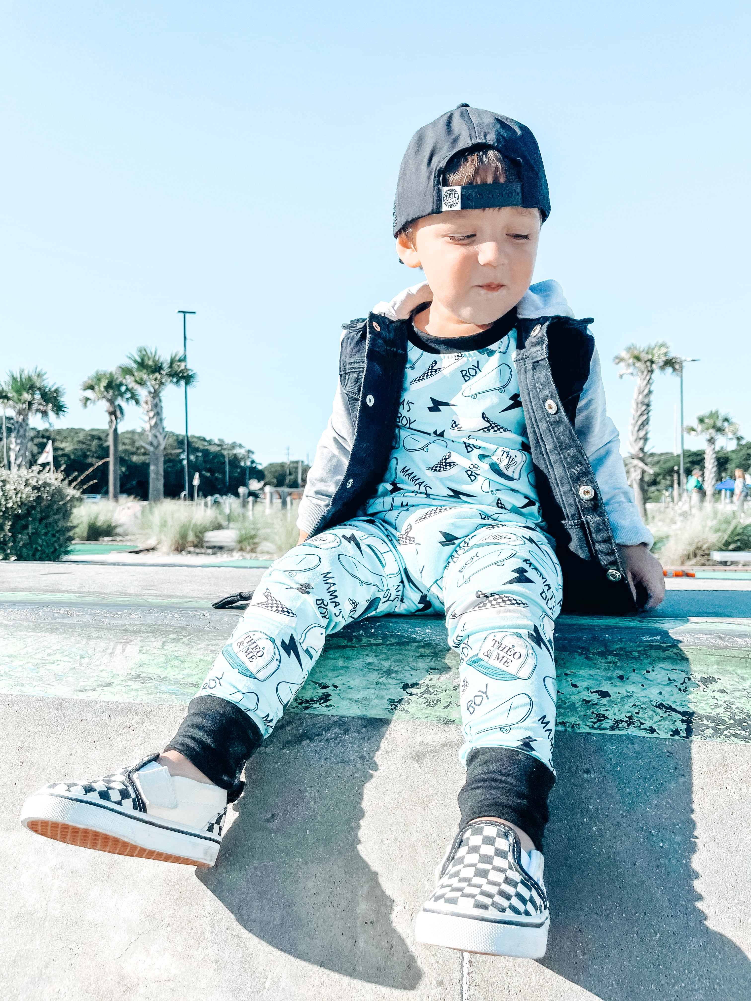 Boy wearing the Boys 2-Piece Short Sleeve Pajamas - Blue Mamas Boy Skateboards plus lightning bolts, sneakers, and theo & me hats as the pattern