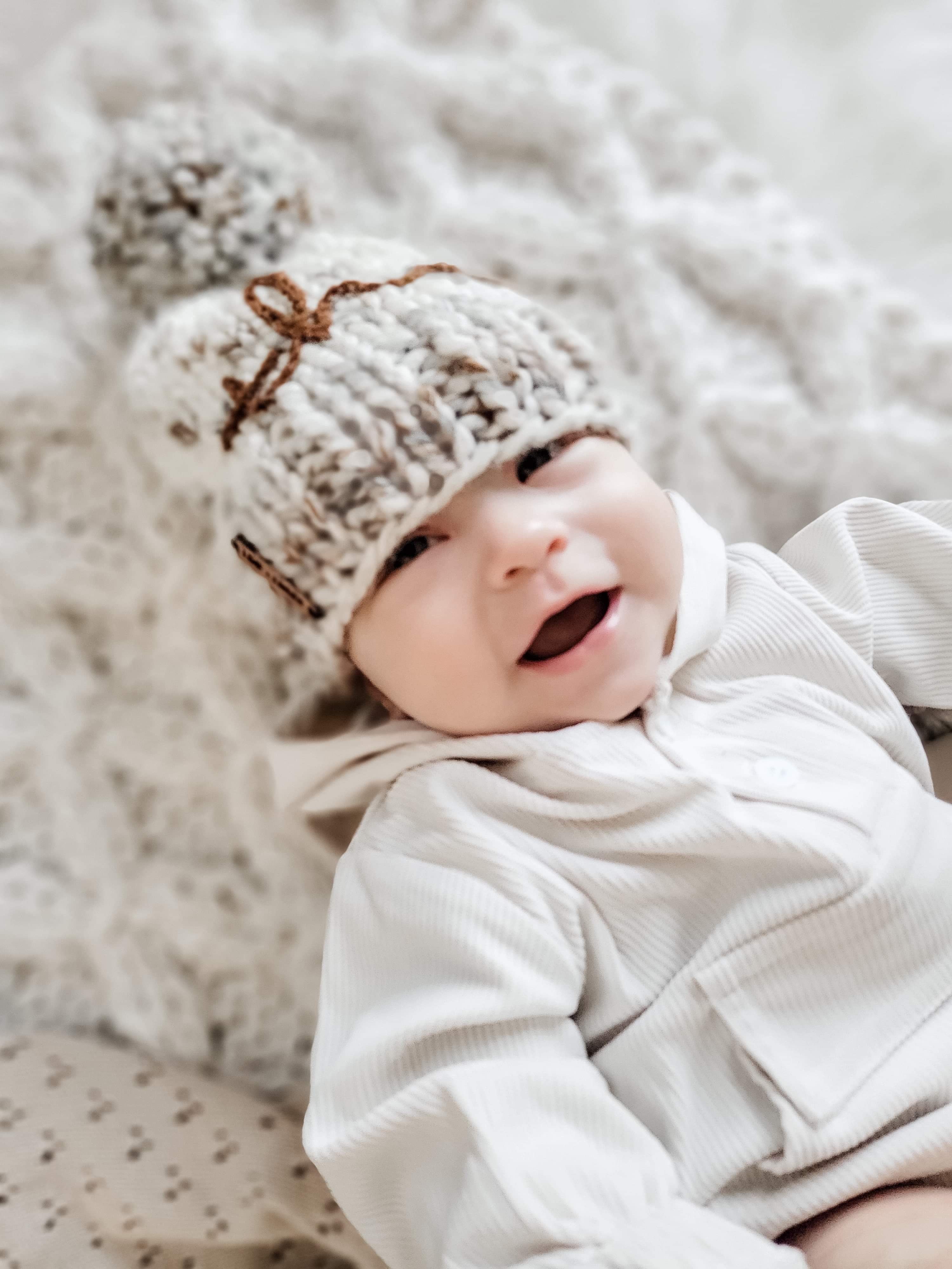 Baby wearing the Kids White Rib Hood Pocket Romper. 2 white buttons at chest, pocket with flap at stomach area, and rouged bits at the wrists. baby is also wearing a knit hat.