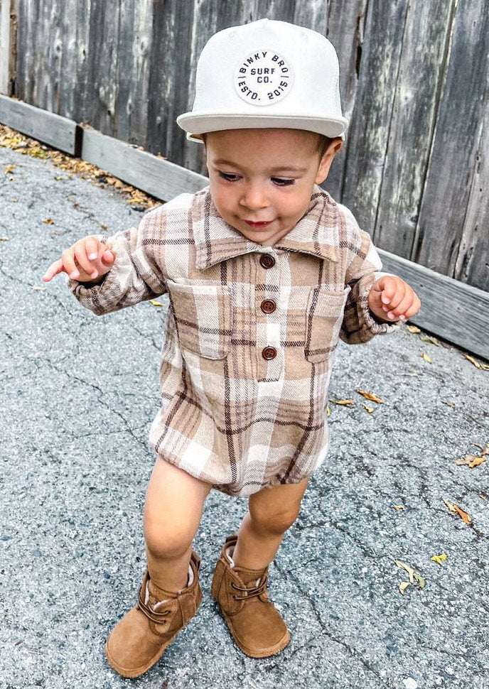 Kid wearing the Kids Dark Tan Plaid Hooded Flannel Romper with white hat & brown boots