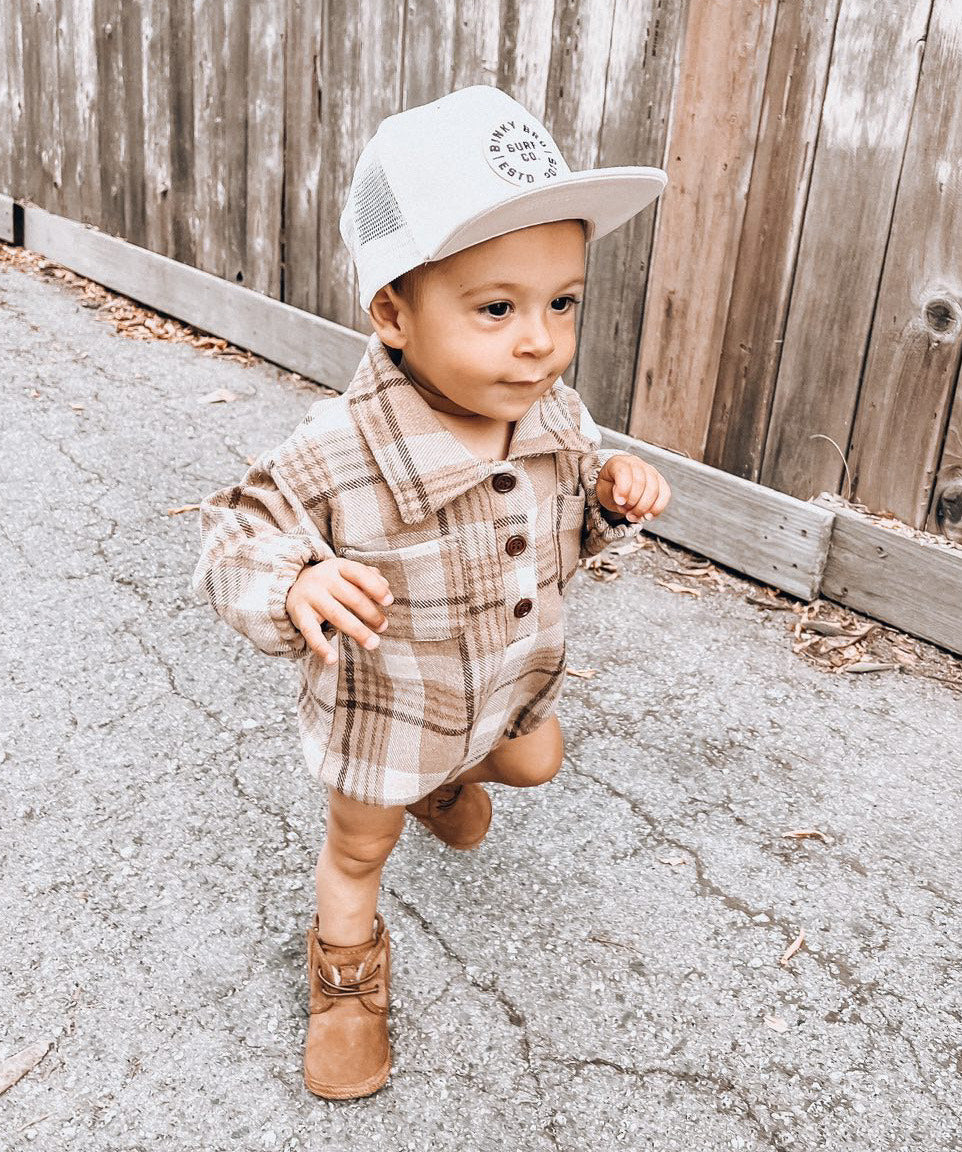 Kid wearing the Kids Dark Tan Plaid Hooded Flannel Romper with white hat & brown boots