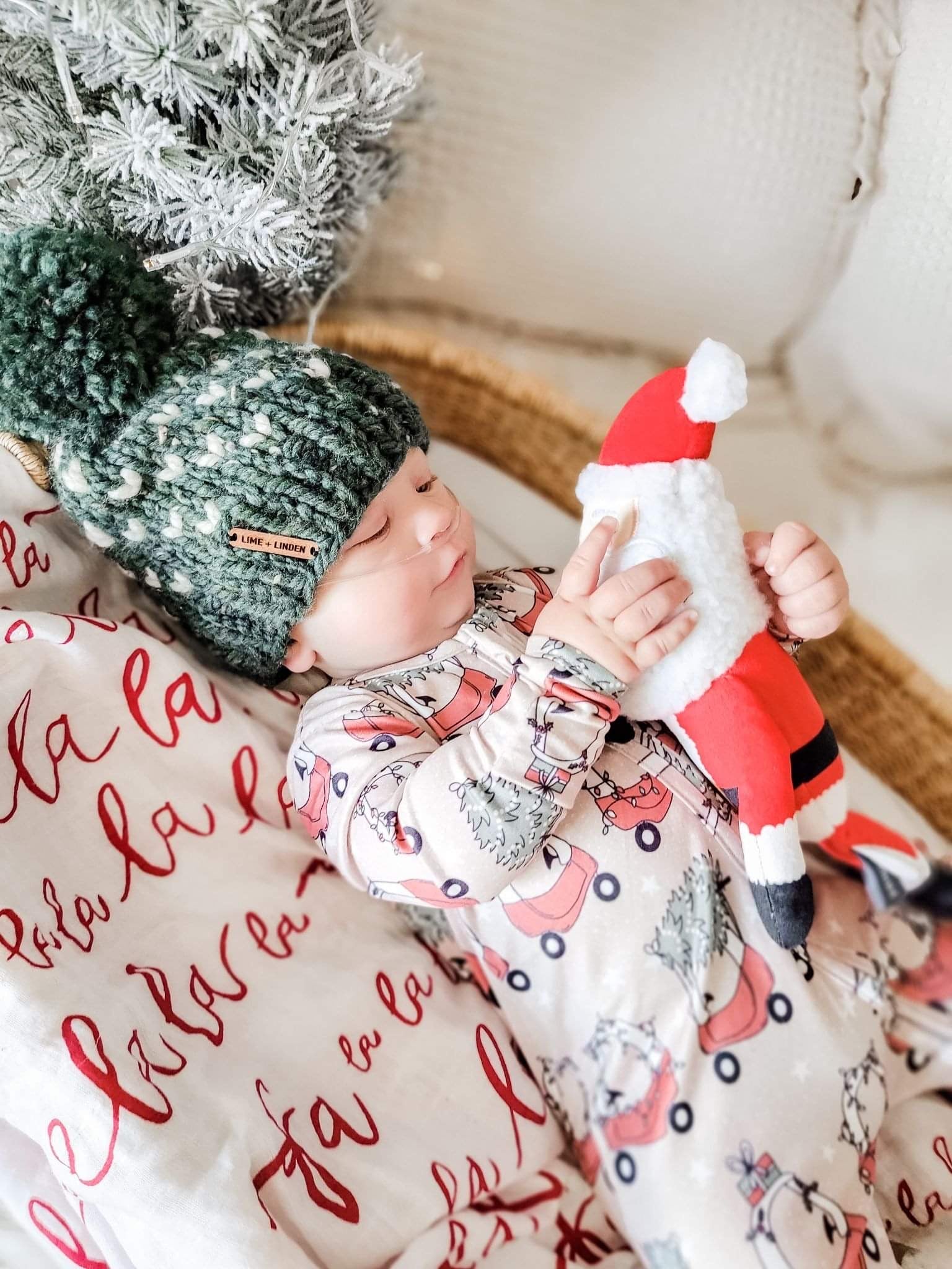 kid wearing the Holiday Baby Zippies Sleepers - Lil Tykes Car Holiday with green knit hat & toy santa