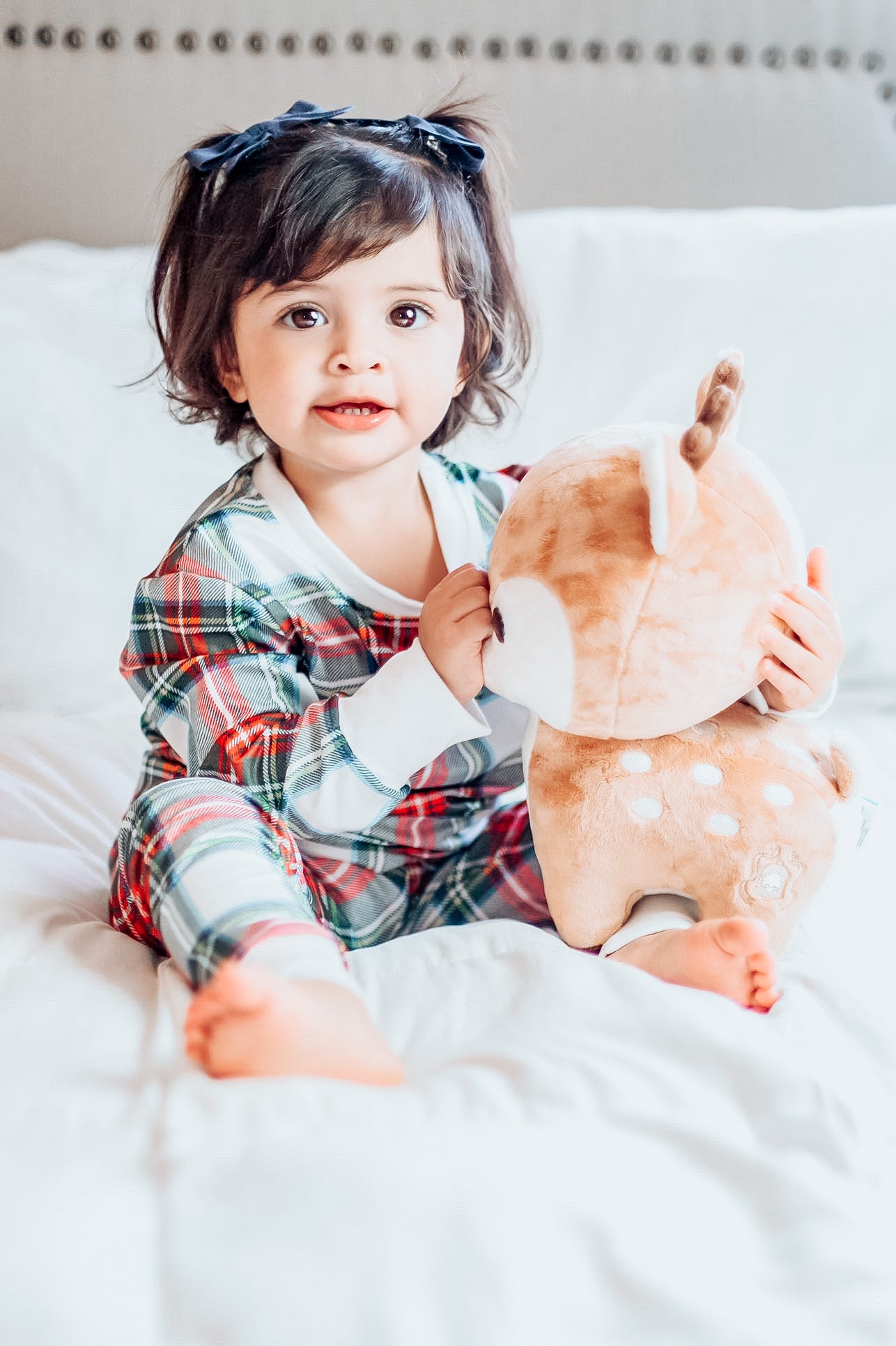 Young child wearing the 2 Pc Christmas Pajamas - Stuart Tartan Holiday Plaid, while playing with a reindeer stuffy.