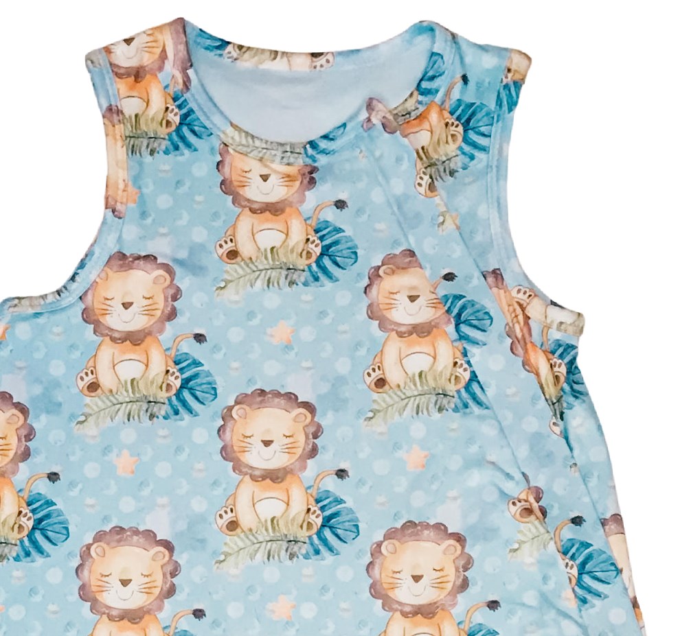 up close details on the baby sleeveless sleep bag with blue background and cartoon lions. Shows zipper located on the right side of the photo. Will be on left side of baby when worn.