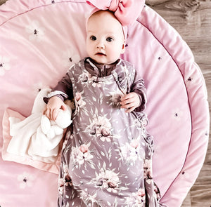 baby wearing the purple peony floral sleep bag. cozy and calm.