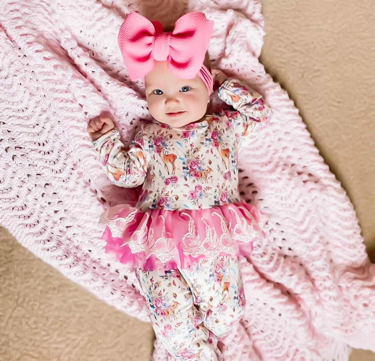 child wearing the Kryssi Kouture Sienna Holiday Infant Deluxe Tutu Jumpsuit - Deer Flora - Tutu. With a pink bow.