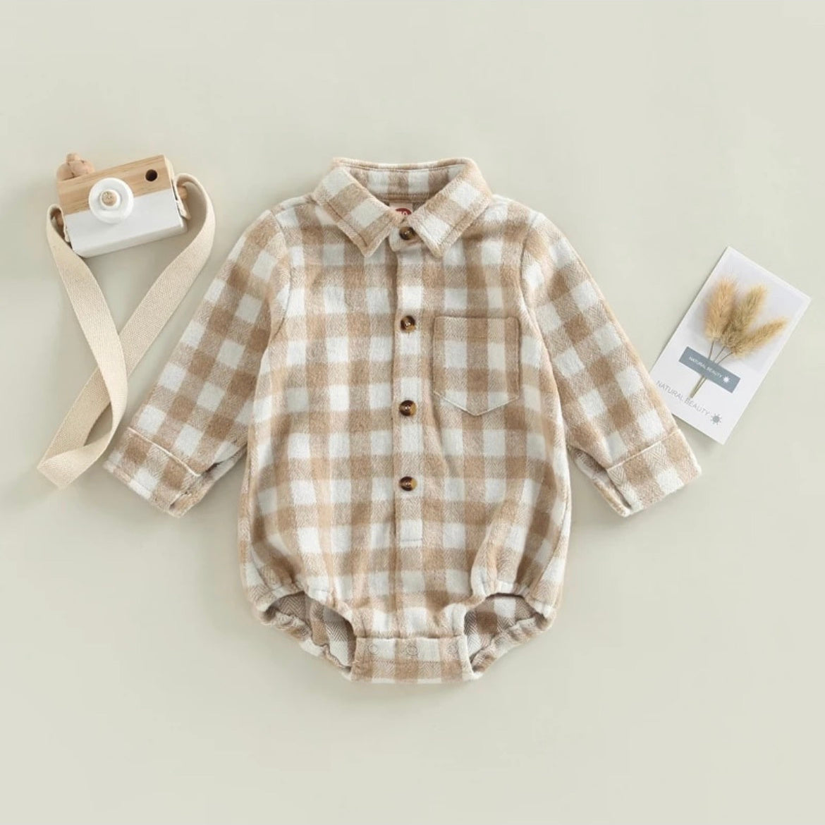 brown check flannel romper with a collar, buttons down the chest, and a pocket over the heart area.