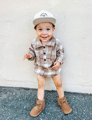 Kid wearing the Kids Dark Tan Plaid Hooded Flannel Romper with white hat & brown boots