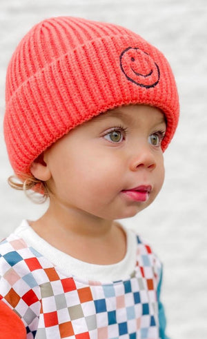 kid in hot pink happy face beanie & checkered sweatshirt
