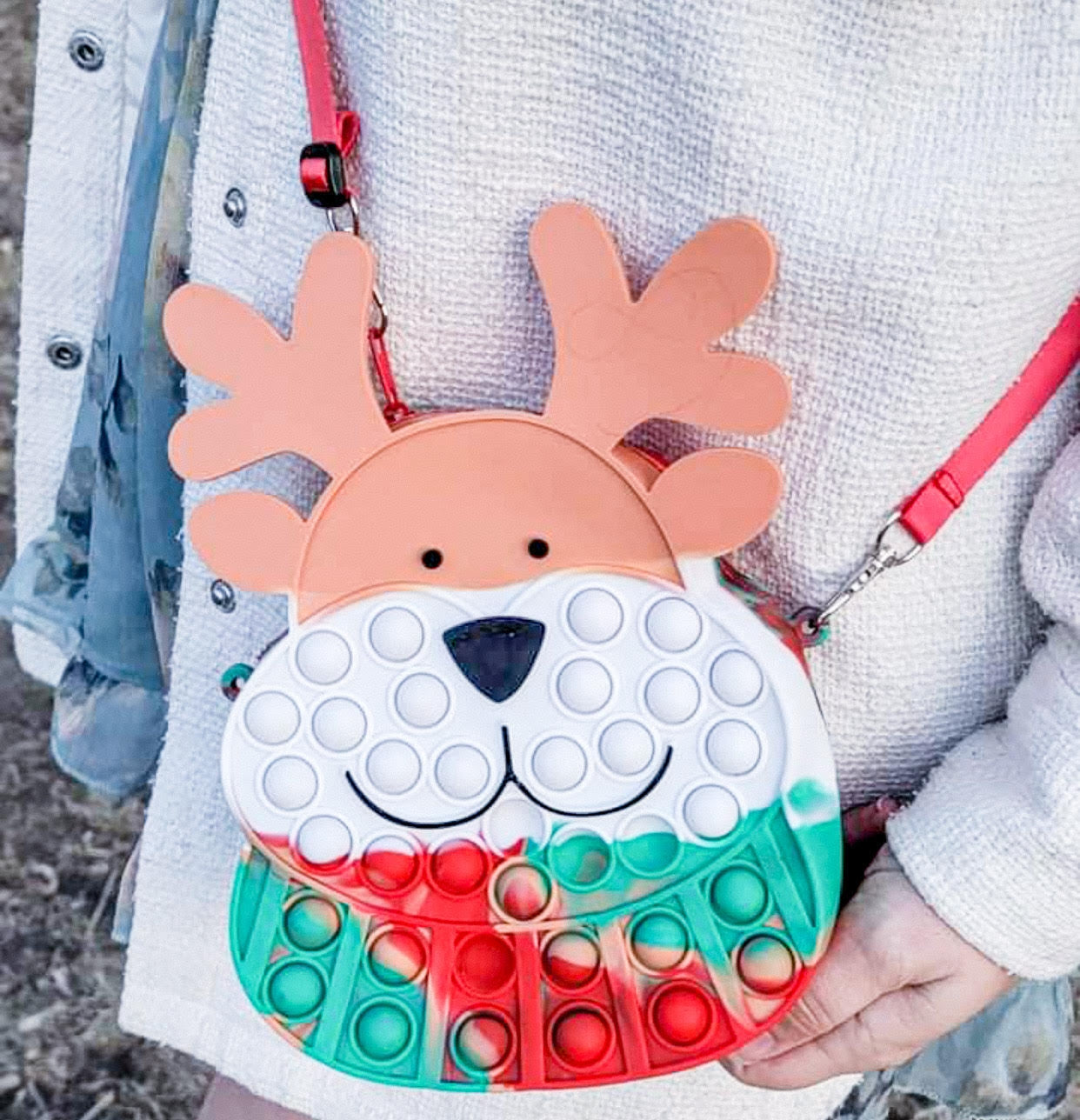 child wearing the reindeer pop-it purse with red strap