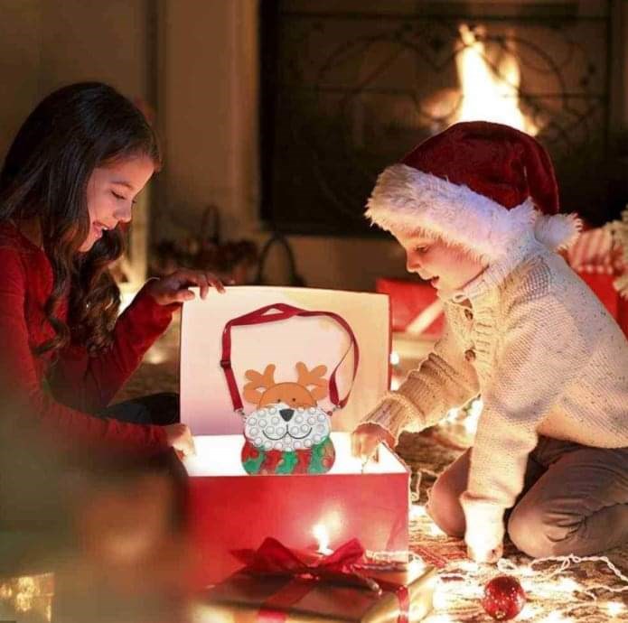kids reindeer pop-it purse with red strap coming out of a red christmas box, surrounded by 2 surprised kids and soft lighting