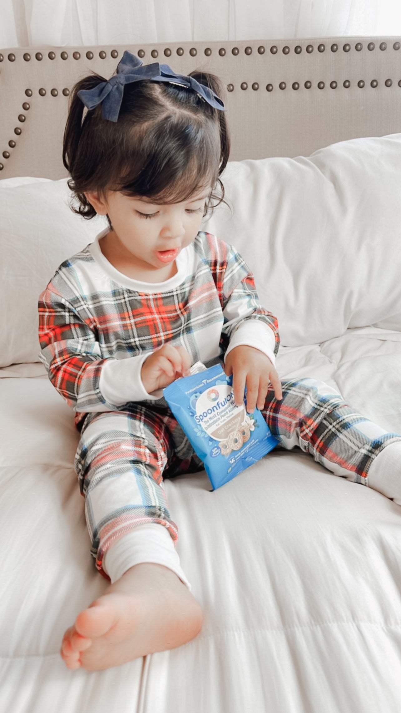 Young child wearing the 2 Pc Christmas Pajamas - Stuart Tartan Holiday Plaid, while snacking on cheerio style snacks.