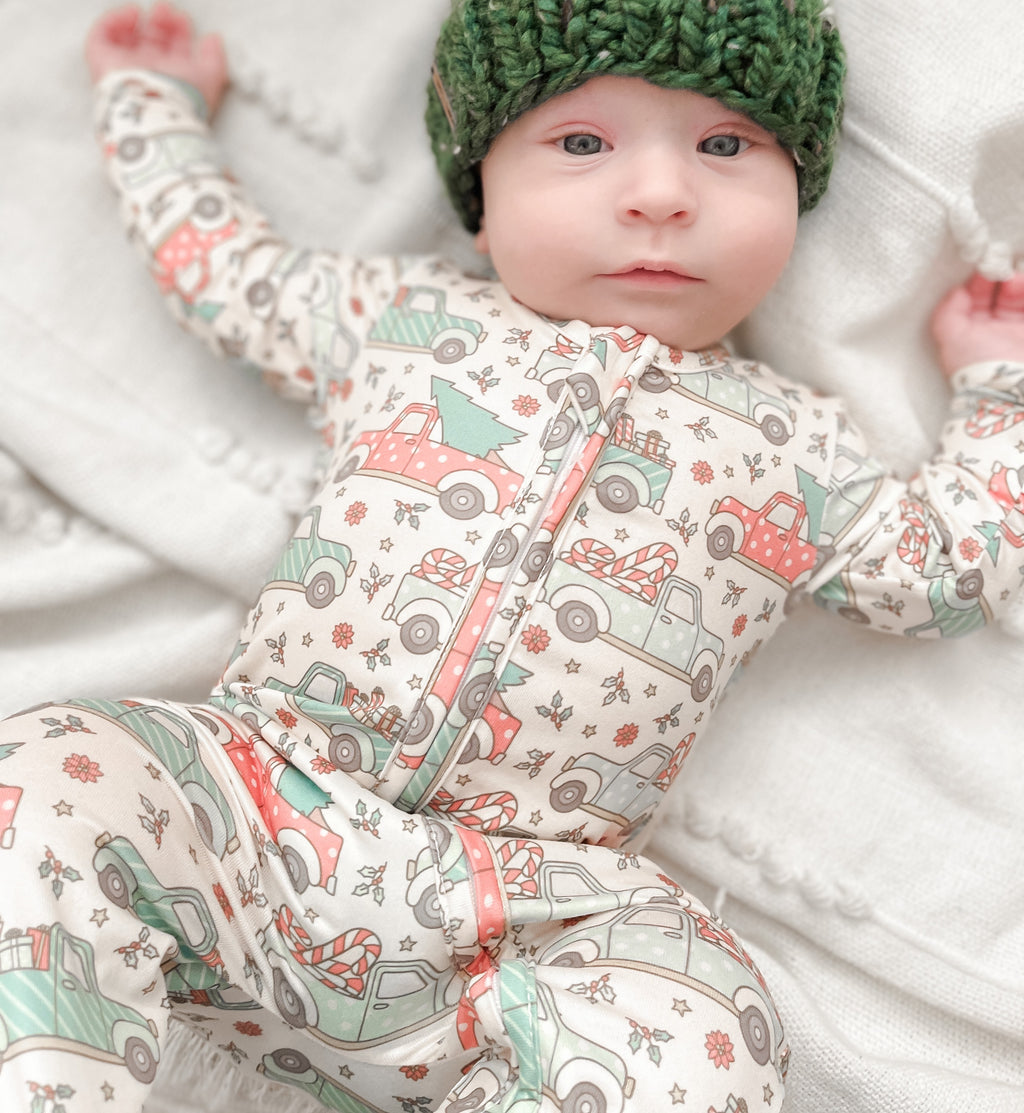 Baby wearing the Beige Vintage Trucks & Trees zippie with green pom hat